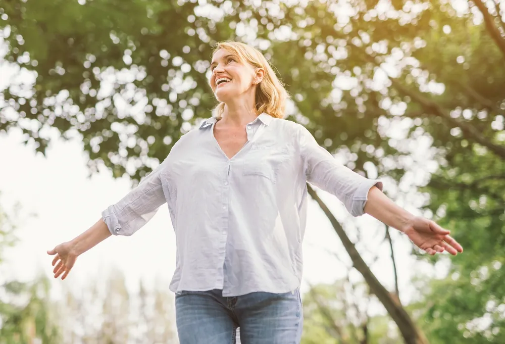 happy woman in spring or summer forest park open arms with happiness, hope and vitality
